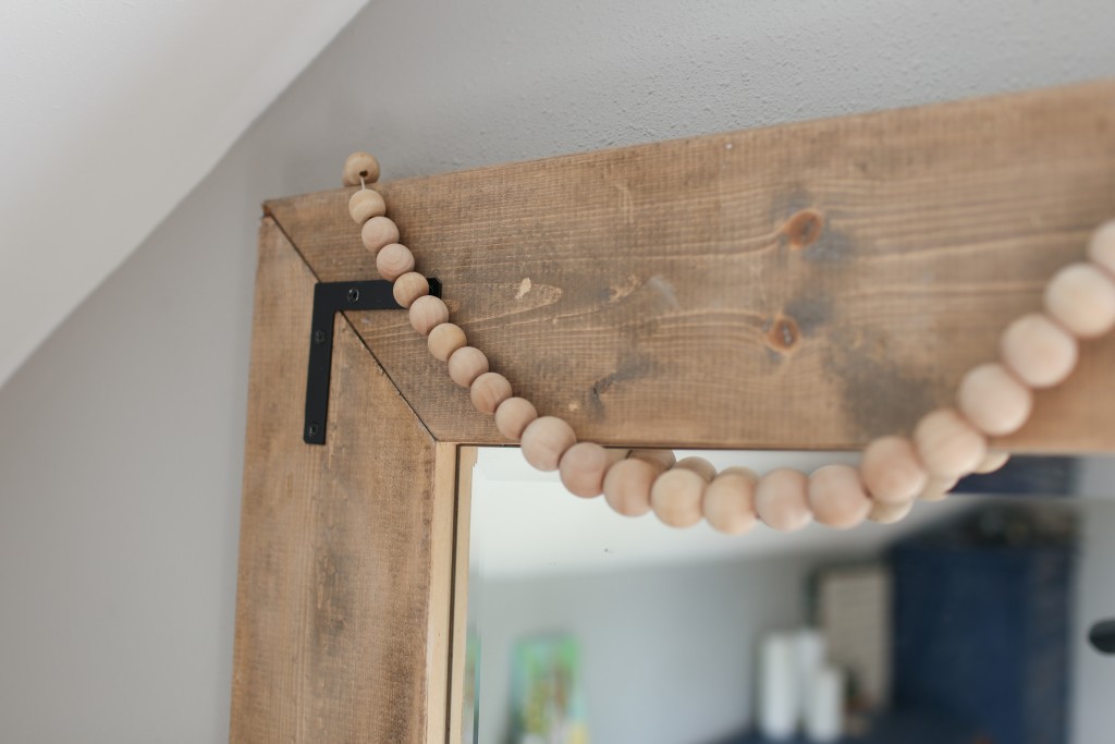 Corner brackets add an industrial touch to the farmhouse floor mirror DIY.  From The Dempster Logbook.