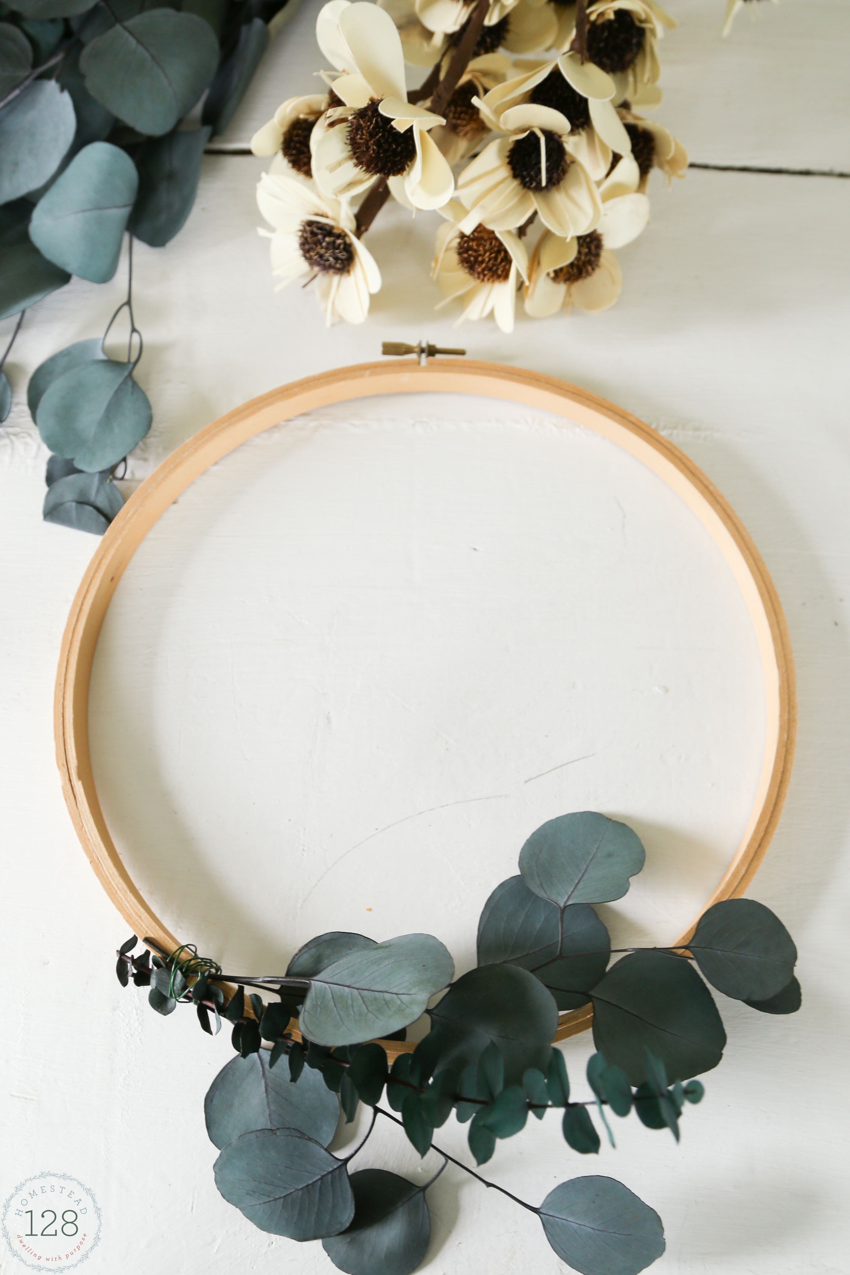 Eucalyptus and white flowered wreath made from embroidery hoops. An easy eucalyptus wreath DIY.