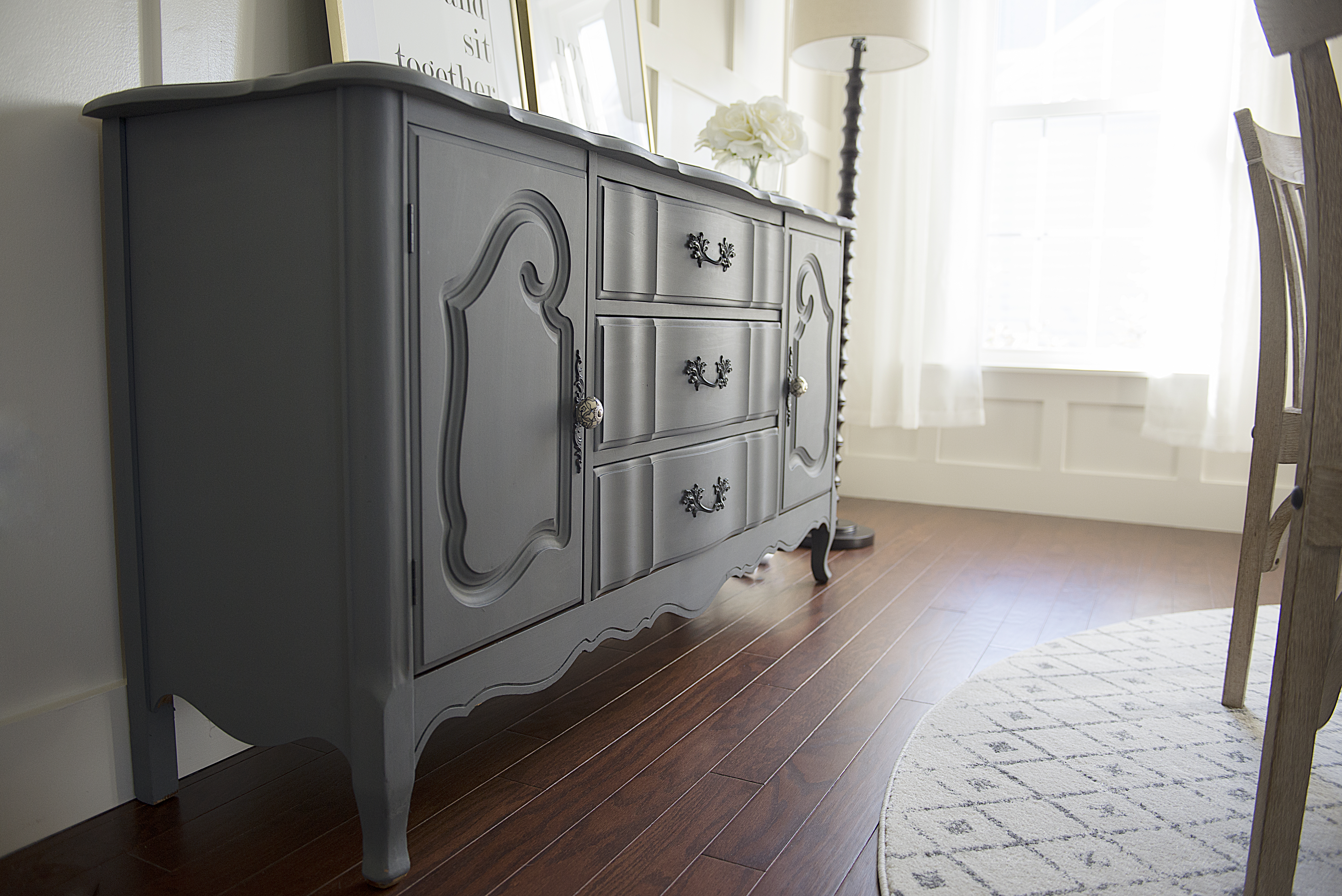 A dark painted buffet agains the white board and batten walls of the transitional dining room.