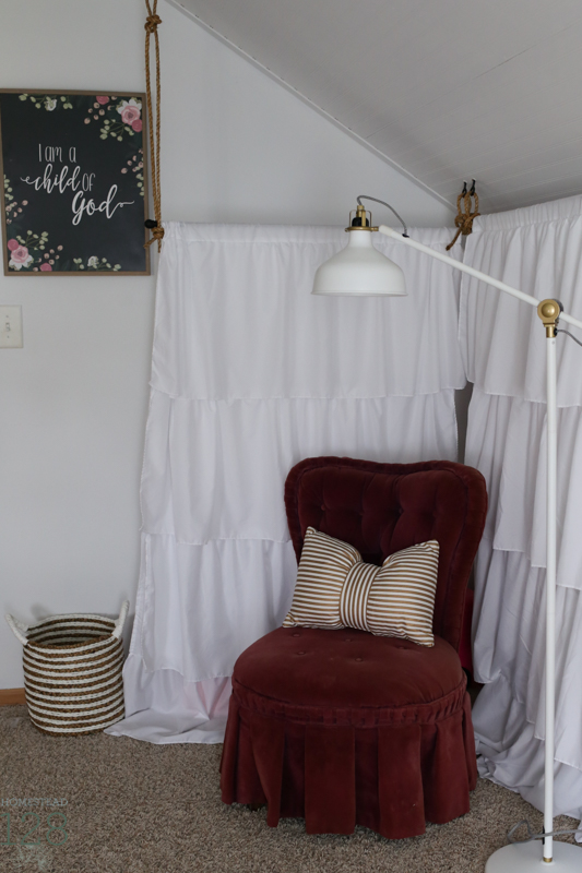 Curtains for hiding toy storage, and a small velvet chair create a reading nook.