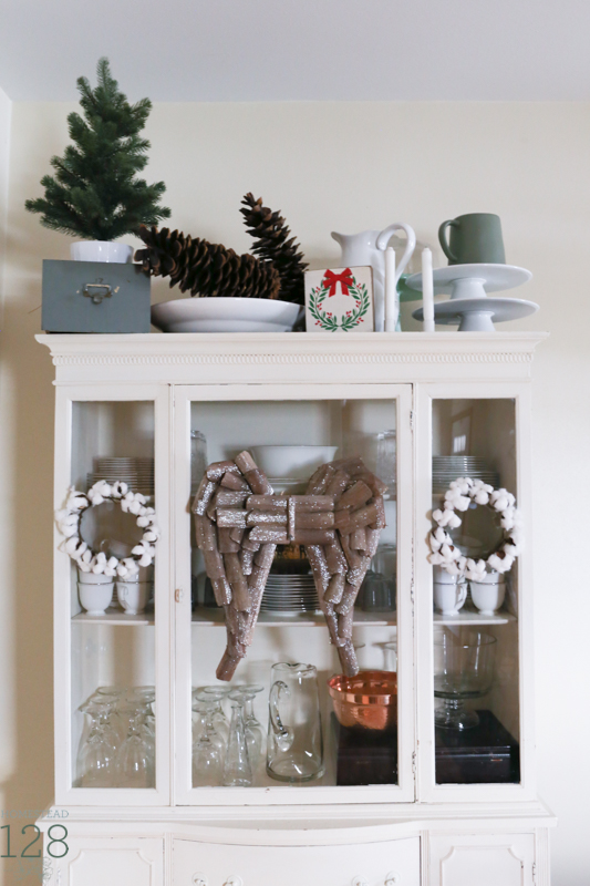 Extra large pinecones with a touch of green, cotton and wooden angel wings decorate the china cabinet at Christmas.
