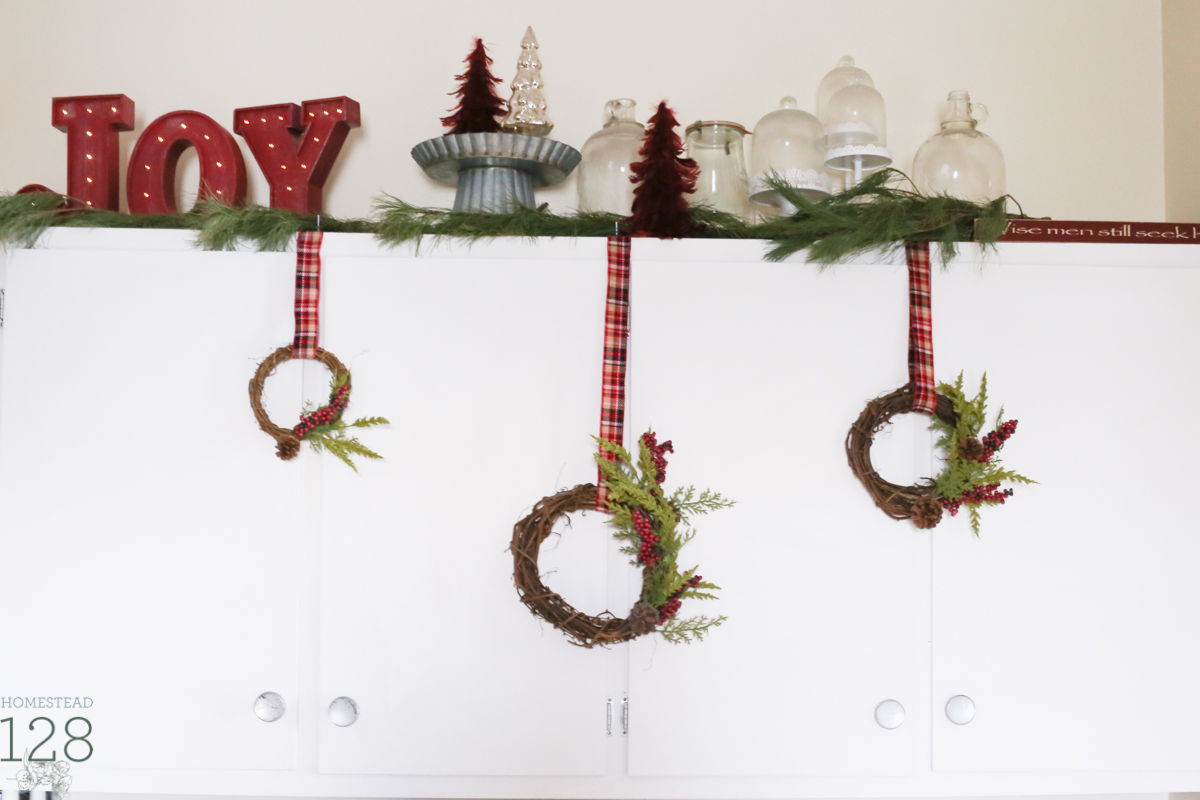 Asymmetrical wreaths hang from storage cupboards in the Christmas farmhouse.