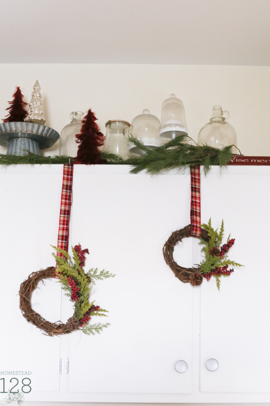 Asymmetrical wreaths hang from storage cupboards in the Christmas farmhouse.