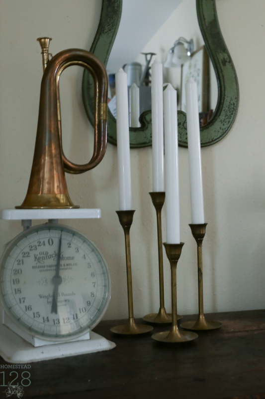 Touches of brass for Christmas with old brass candlesticks and horn along with a white scale.