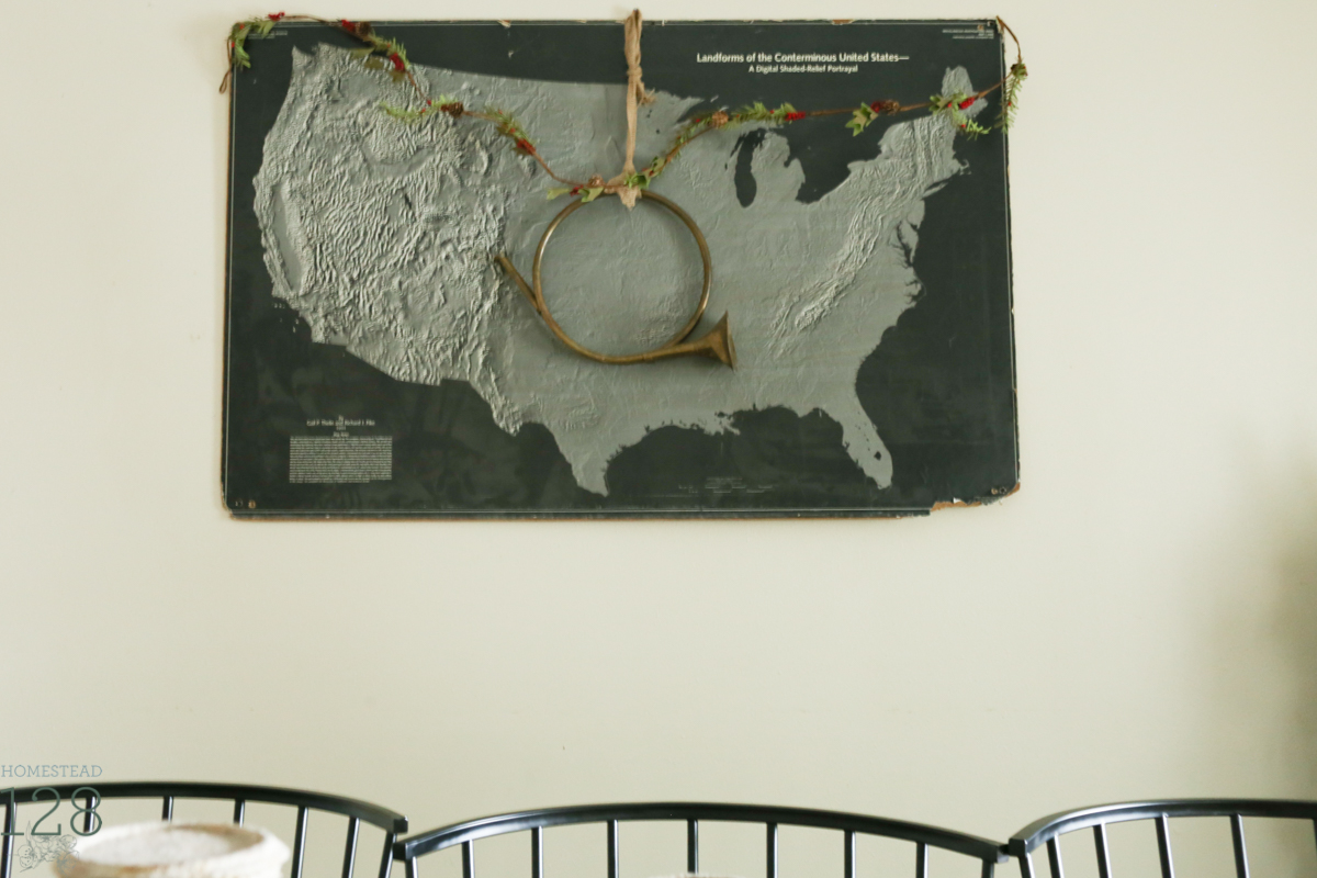 Vintage and torn black and white school map is decorated with some simple garland and a brass horn for Christmas.