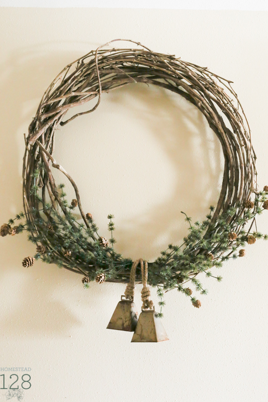 Simple Christmas wreath. Farmhouse Christmas decorating. Extra large wreath hung in the hallway with faux pine branches and brass bells.