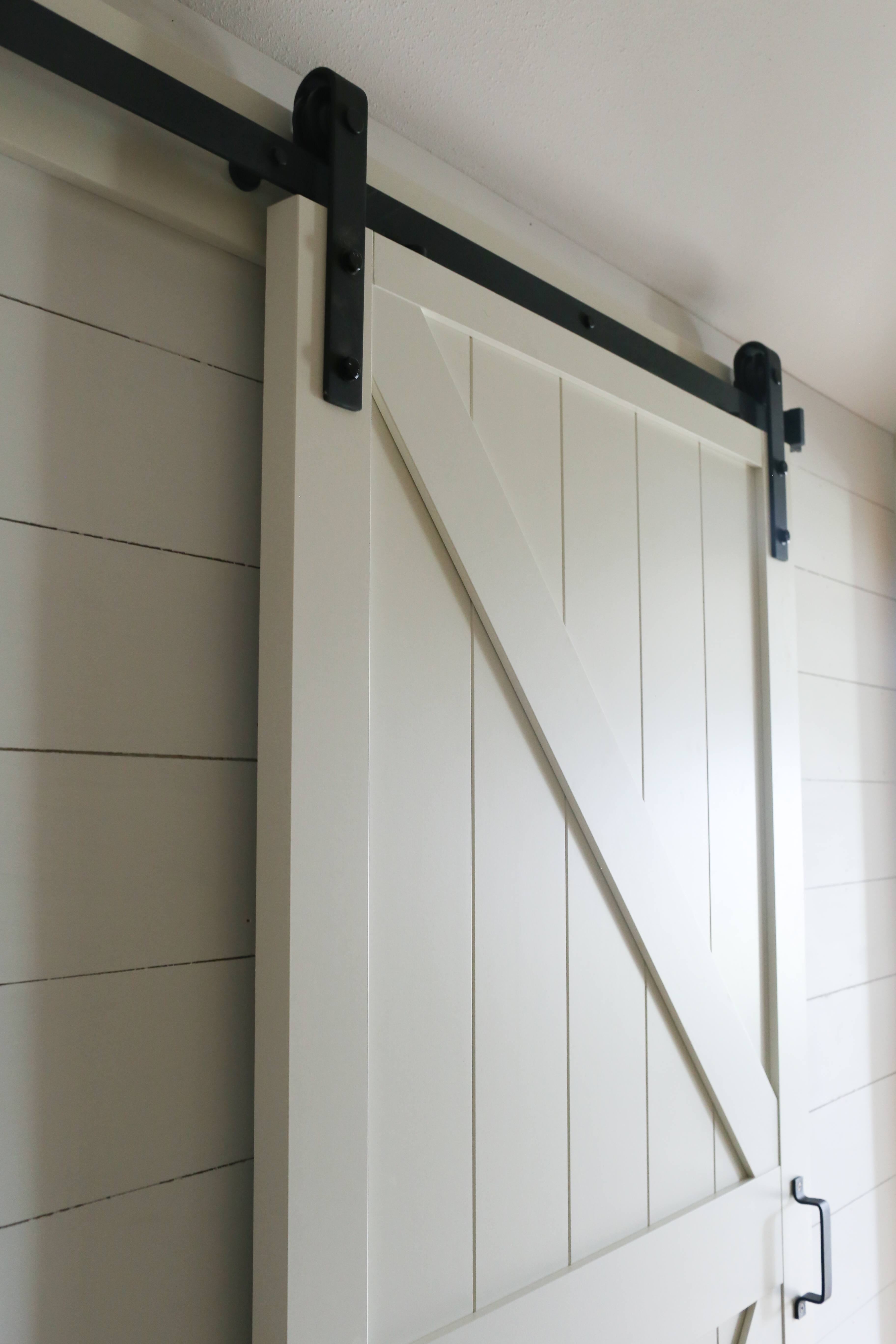 The modern farmhouse hallway is updated with white faux shiplap and a sliding barn door.