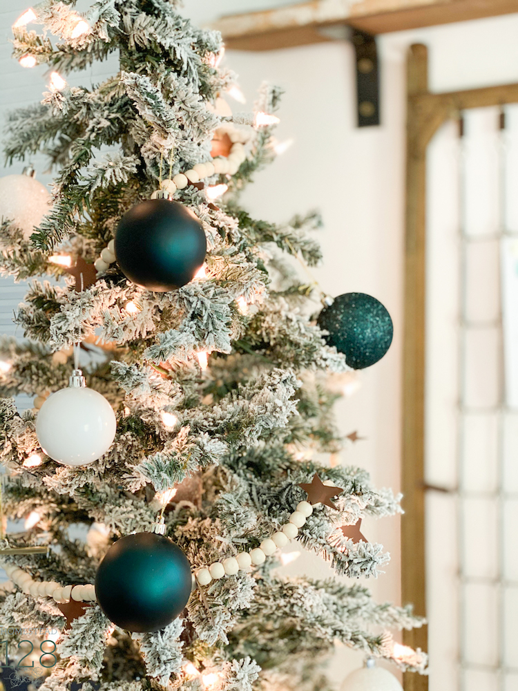 A flocked alpine style Christmas tree decorated with whites and sea green.